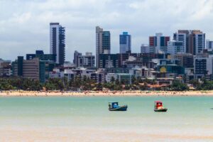 Mar com barcos e ao fundo os prédios de João Pessoa